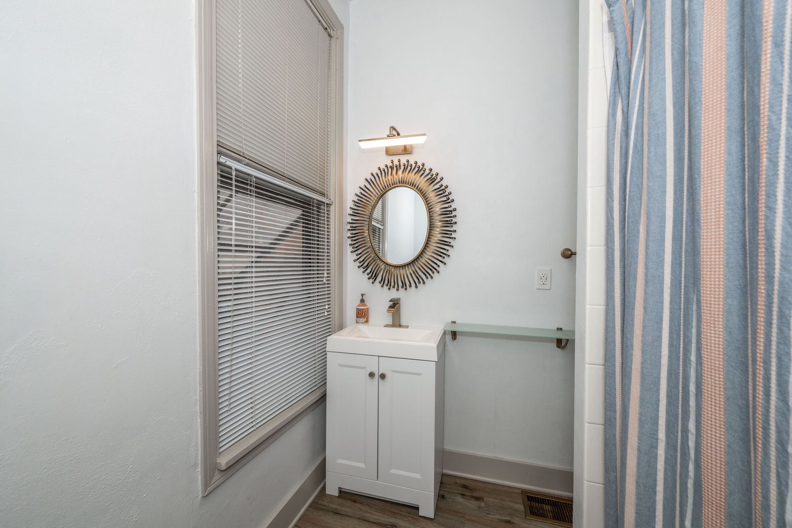The full bathroom features a sleek single vanity & shower/tub combo
