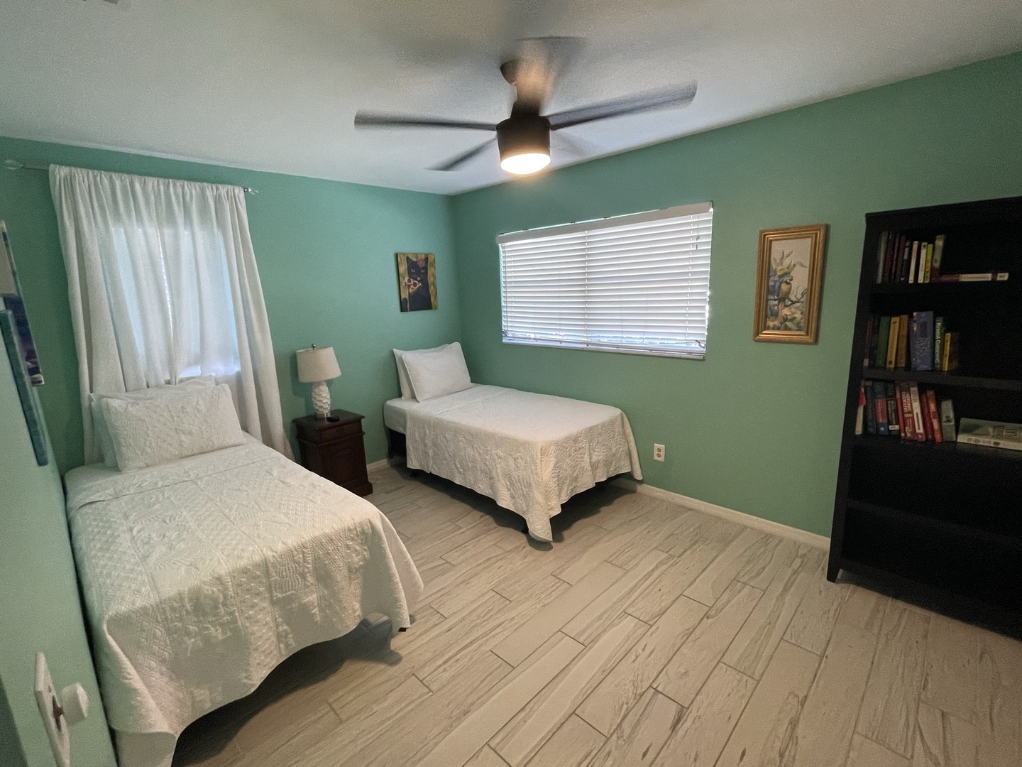 The second bedroom includes a pair of cozy twin beds & ceiling fan