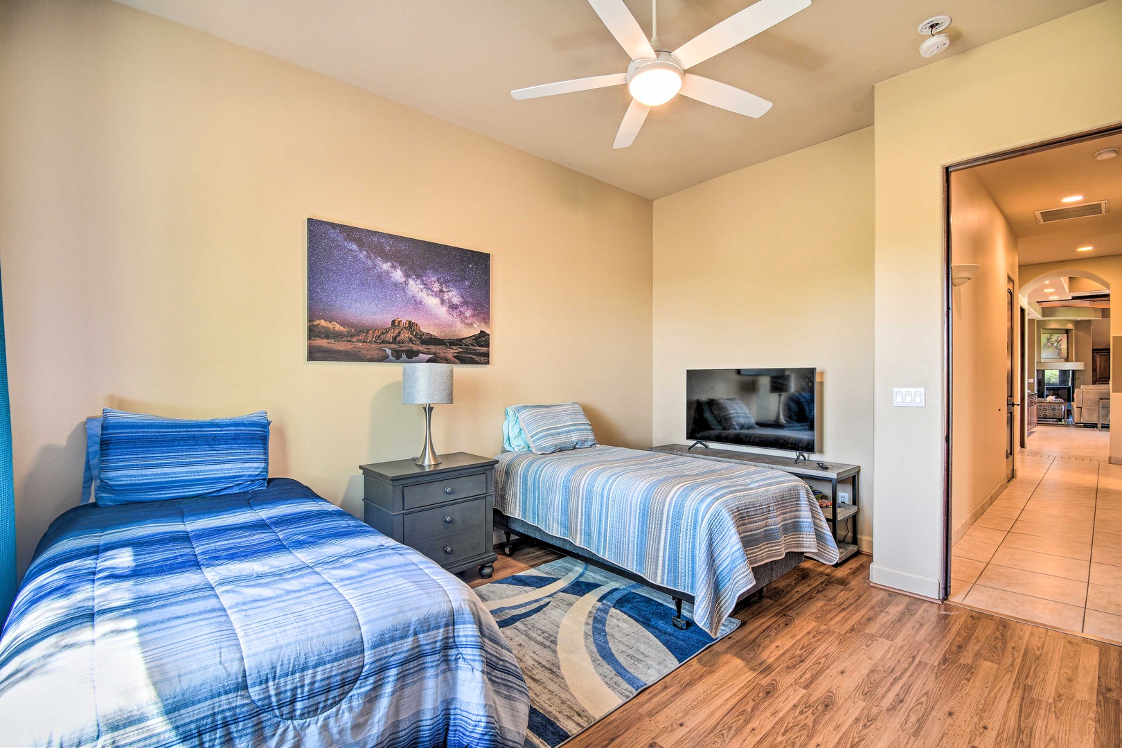 This bedroom includes a pair of twin beds, Smart TV, & ceiling fan