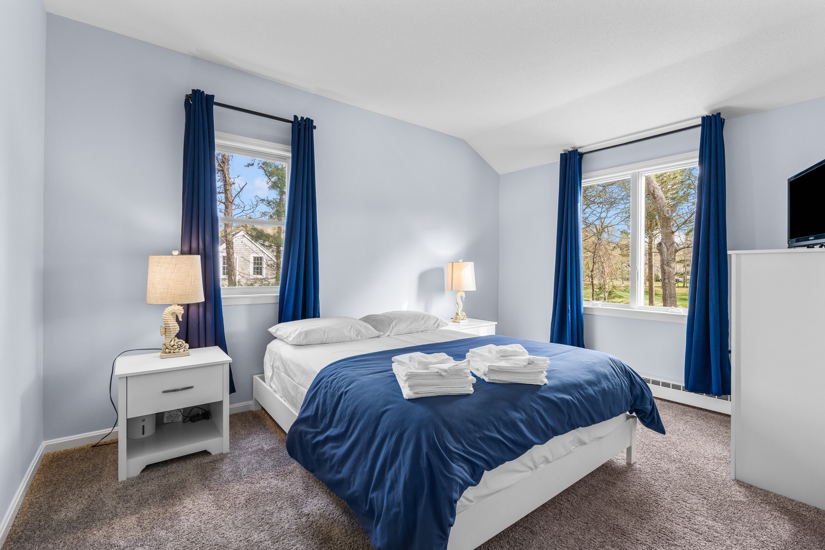 The first of two 2nd-floor bedrooms includes a cozy queen bed & TV