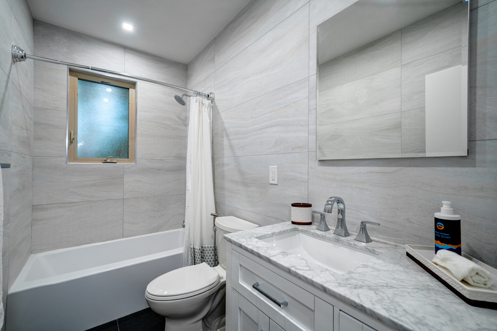 This lower-level full bath features a chic single vanity & shower/tub combo