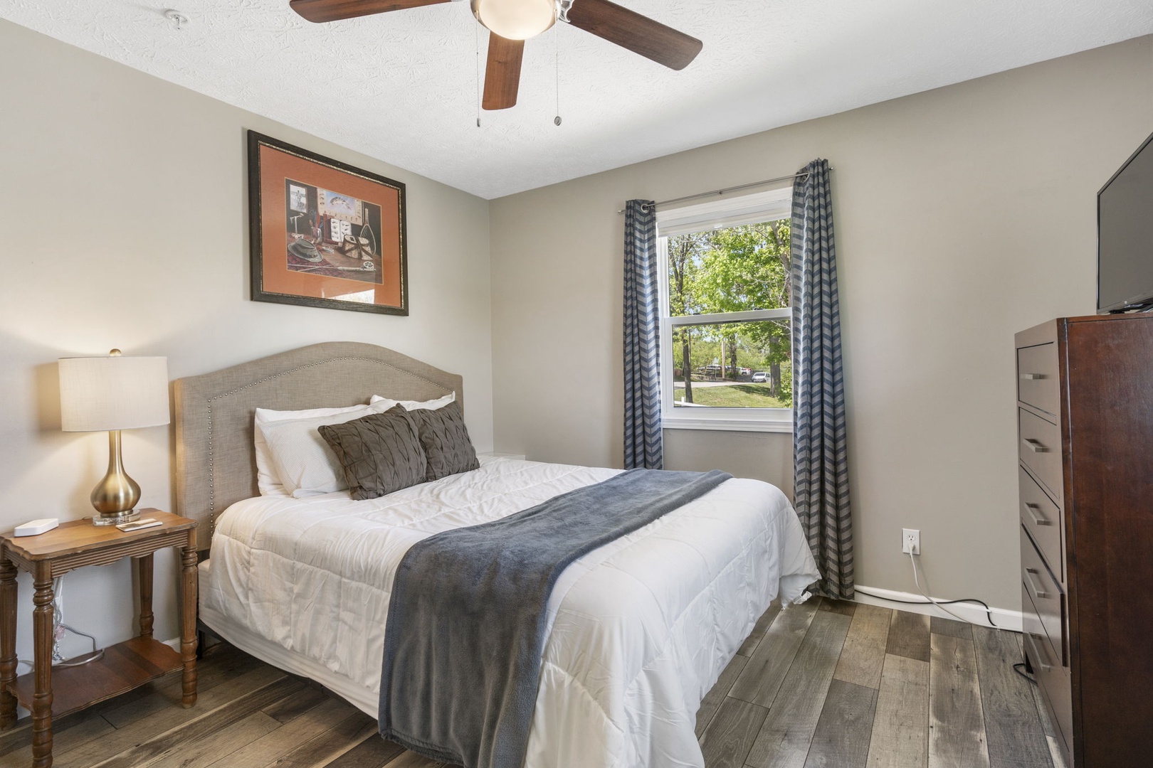 This elegant queen bedroom offers a Smart TV & ceiling fan