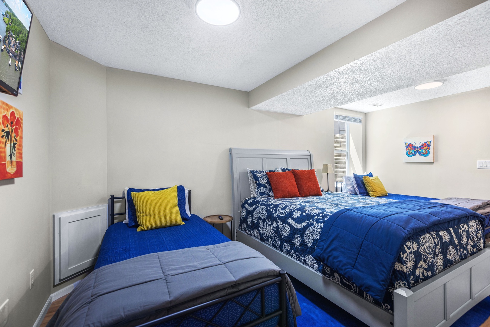 The lower-level bedroom offers a queen bed, a pair of twin beds, & Smart TV