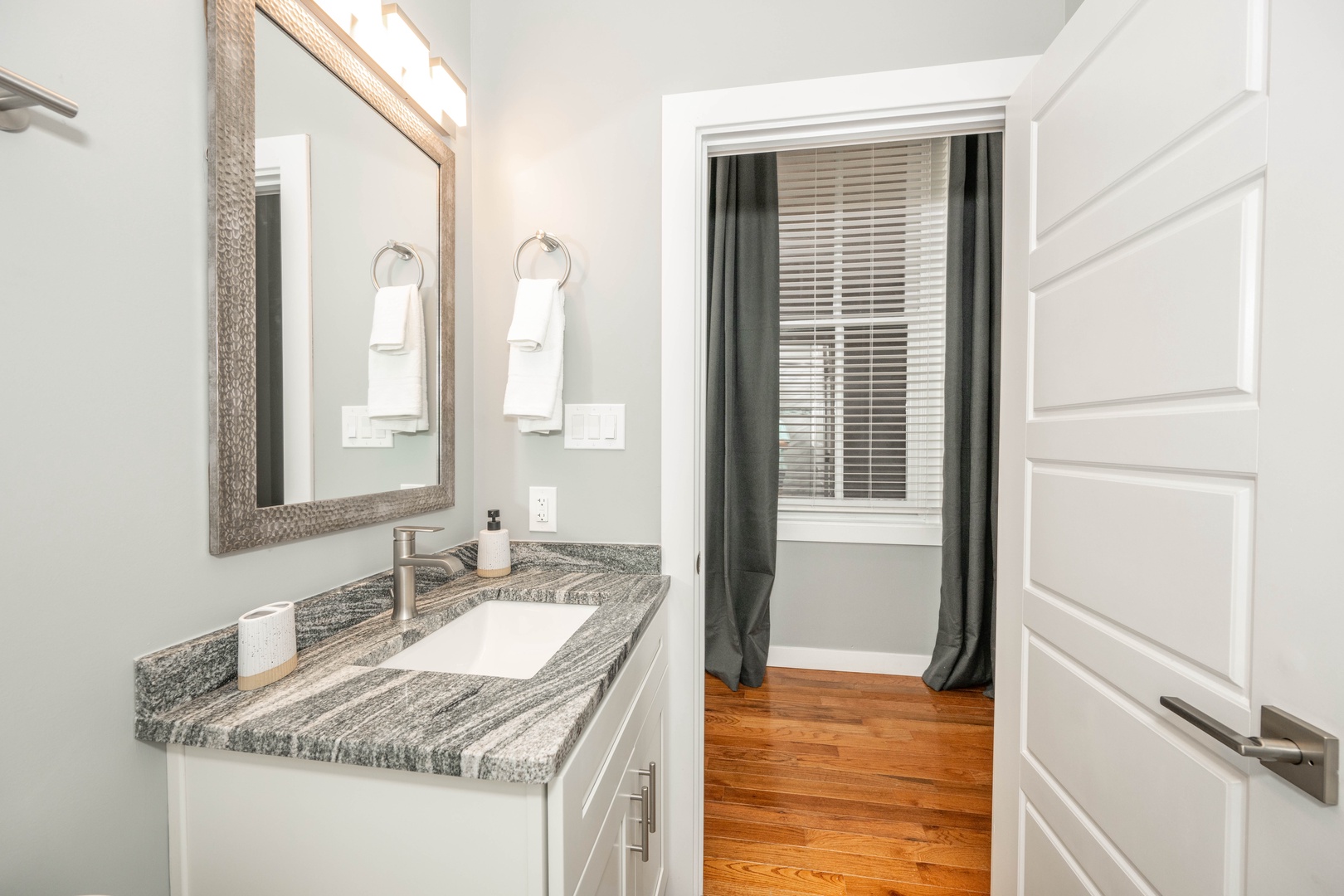 The chic full bathroom offers a single vanity & shower/tub combo