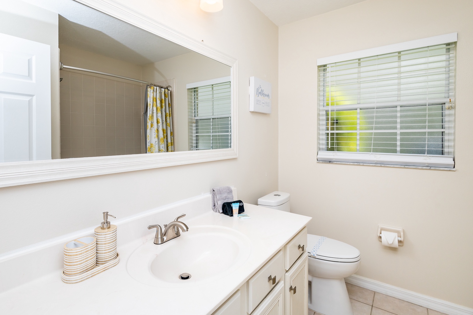 This shared bathroom contains a single vanity & shower/tub combo