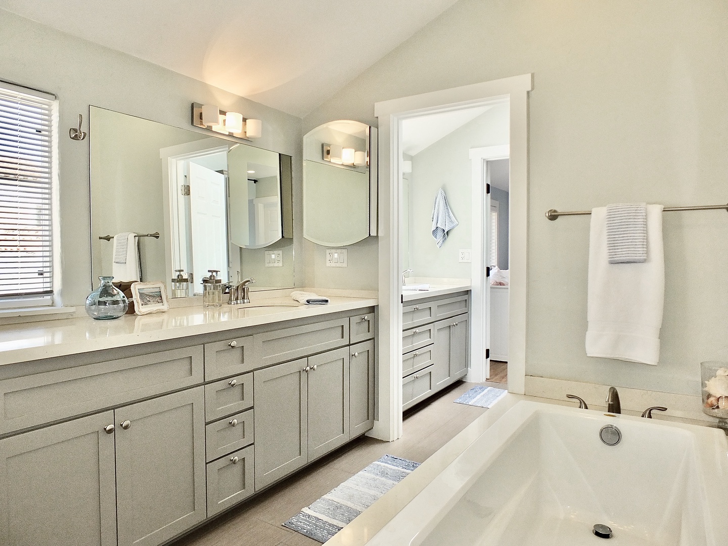 Dual vanities, a glass shower, & luxe soaking tub await in this full bath