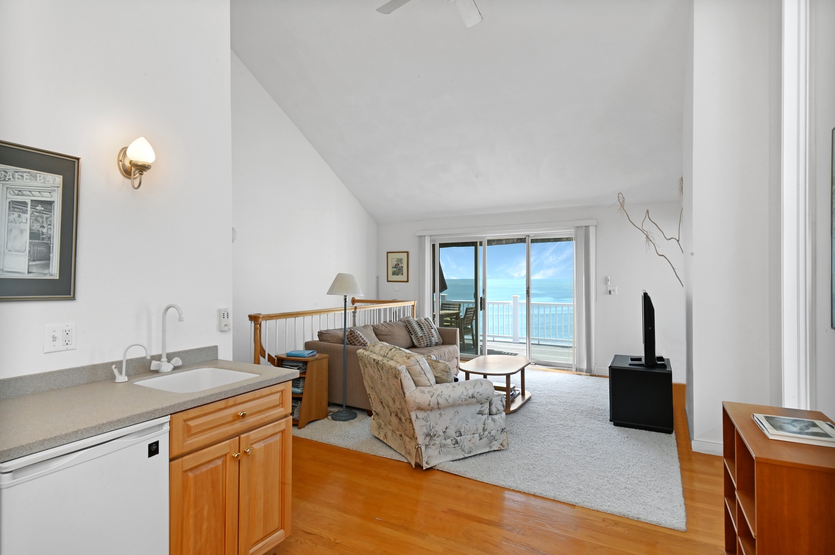 Upstairs living area with cozy seating, TV, work station, and balcony