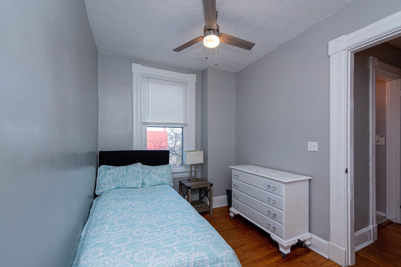 This cozy bedroom offers a twin bed, dresser, & ceiling fan