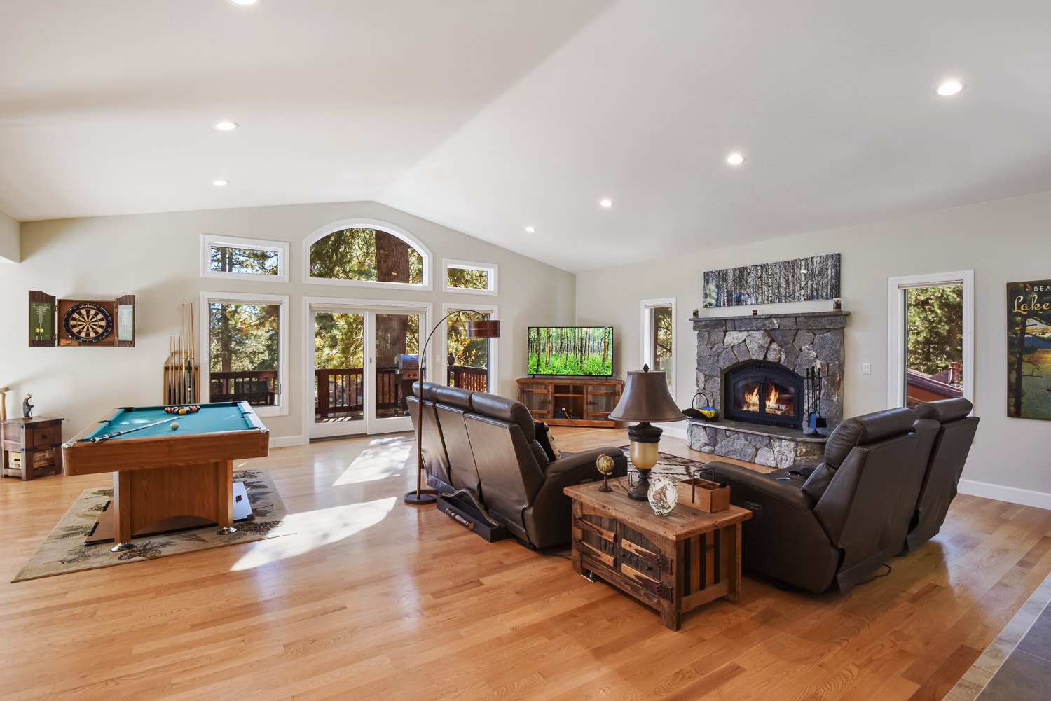 Open living space with pool table, dart set, gas fireplace, Smart TV, and deck access