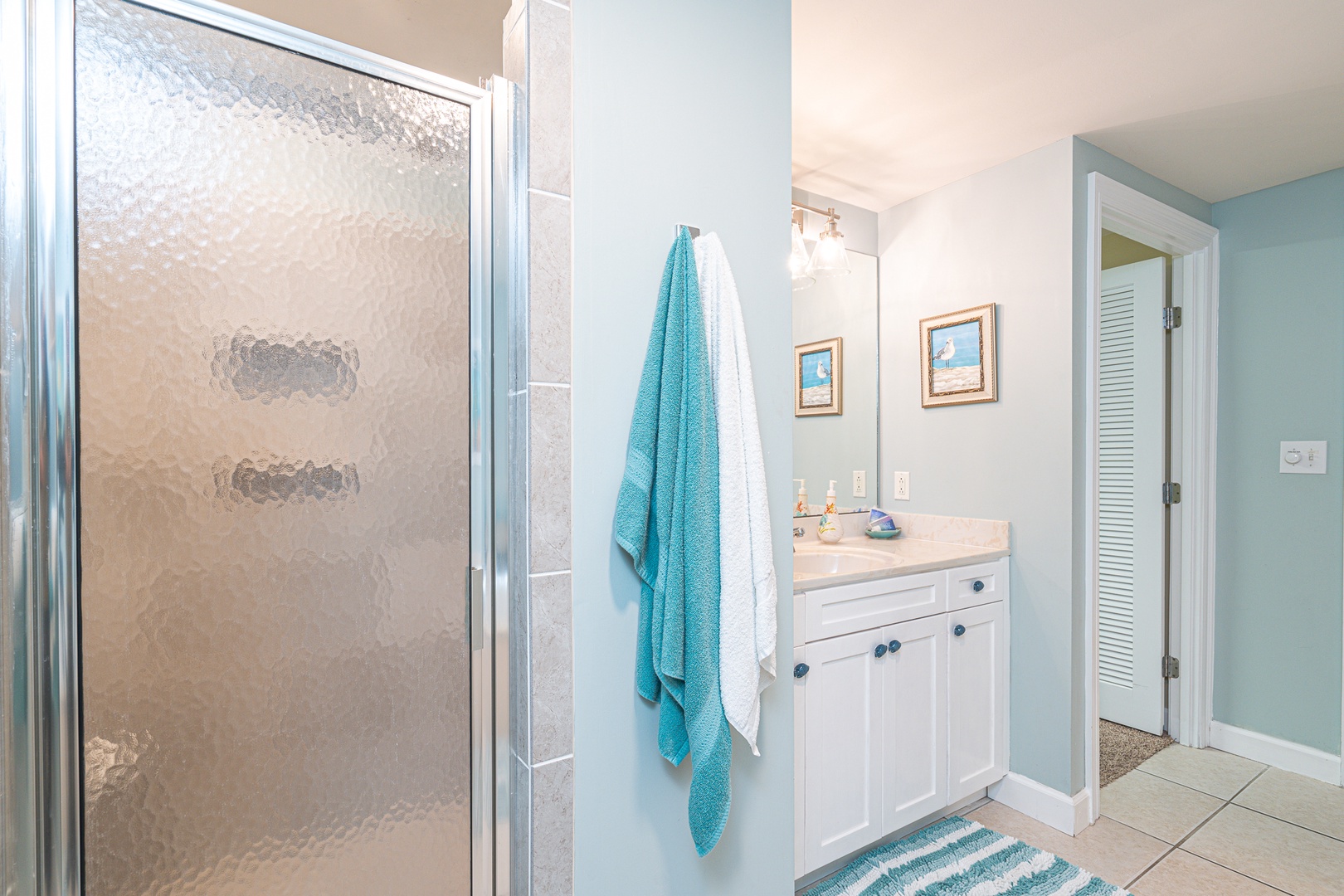 This ensuite bath features a single vanity, Jacuzzi tub, & glass shower