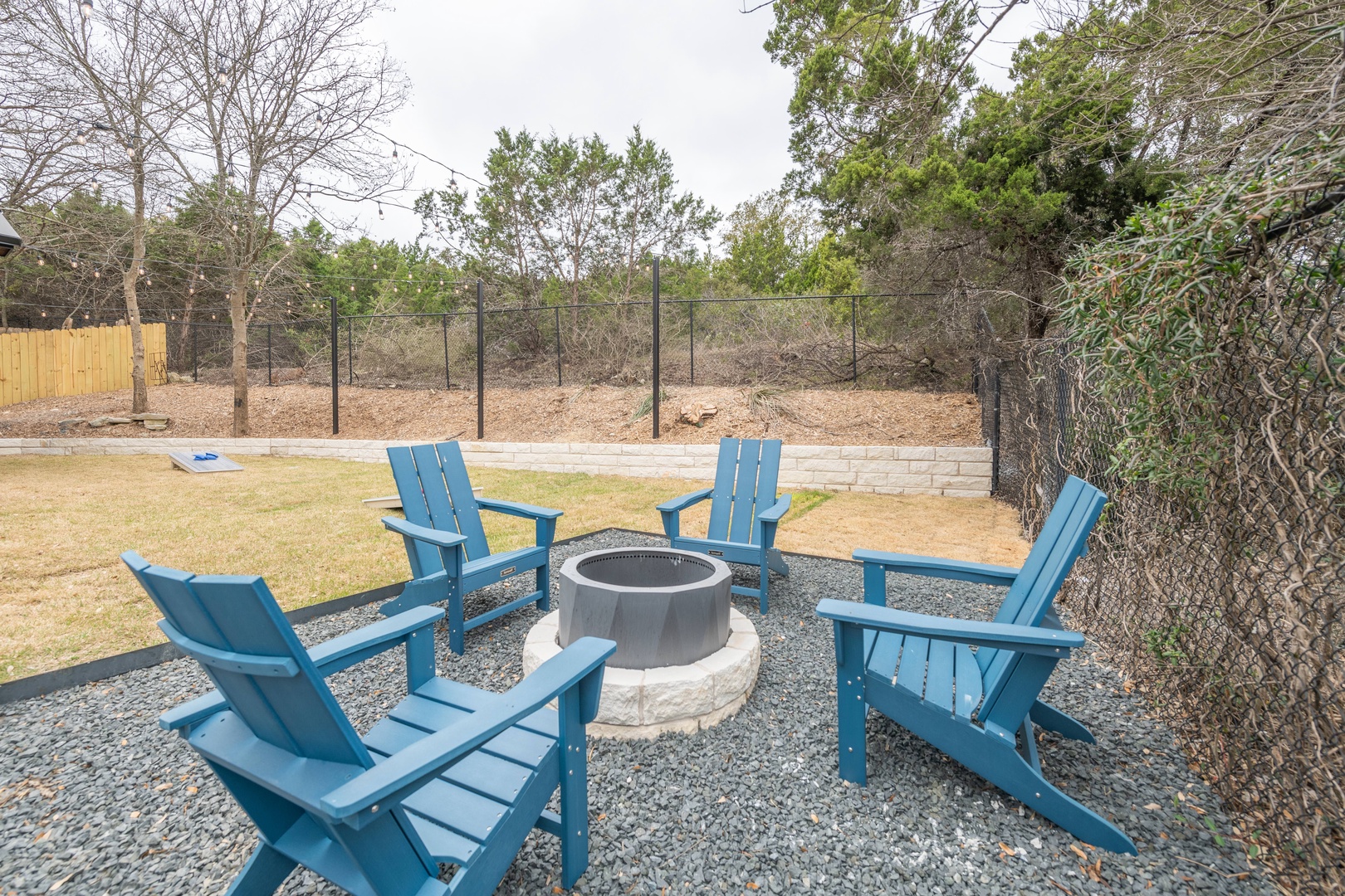 Back yard with more seating, grill, firepit, and corn hole
