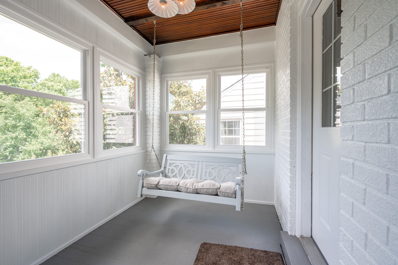 Unit 2 – The sunroom porch swing is the perfect spot for relaxing with a book