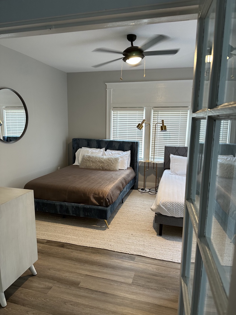 The stylish bedroom includes 2 queen beds, ceiling fan, & dresser