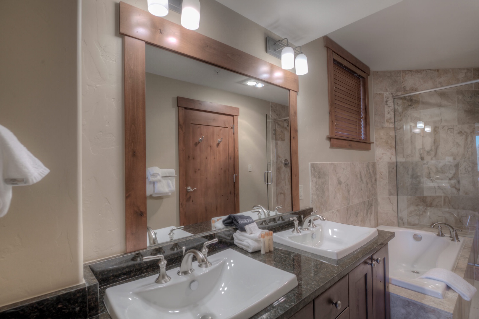 En suite bathroom with standing shower, soaking tub, and dual sinks