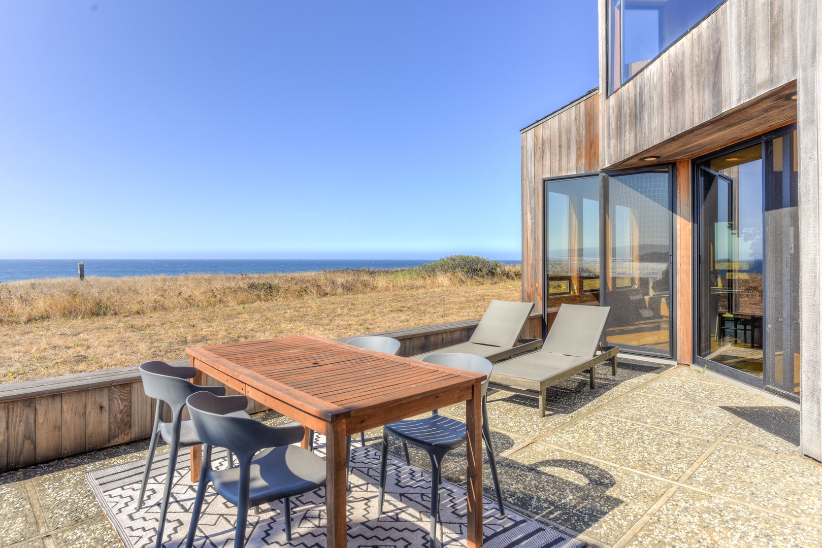 Outdoor seating for 4 and lounge chairs with ocean views