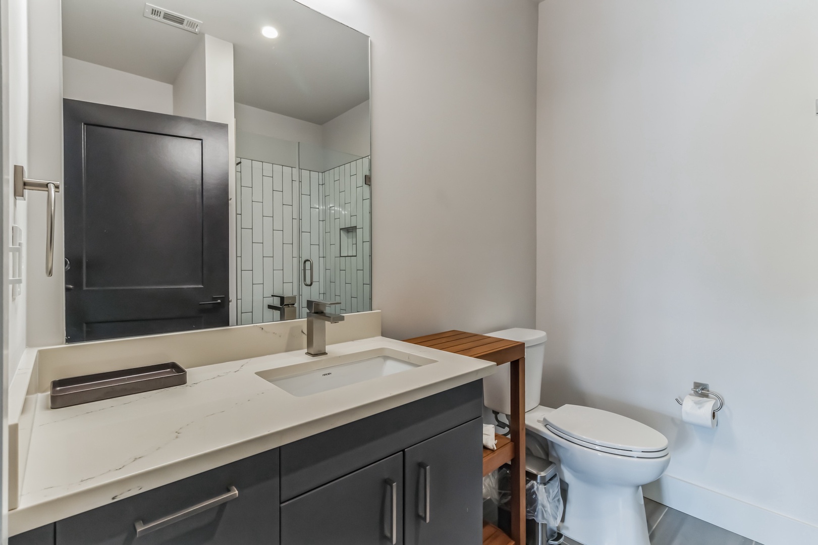 The ensuite features a single vanity, glass shower, & laundry