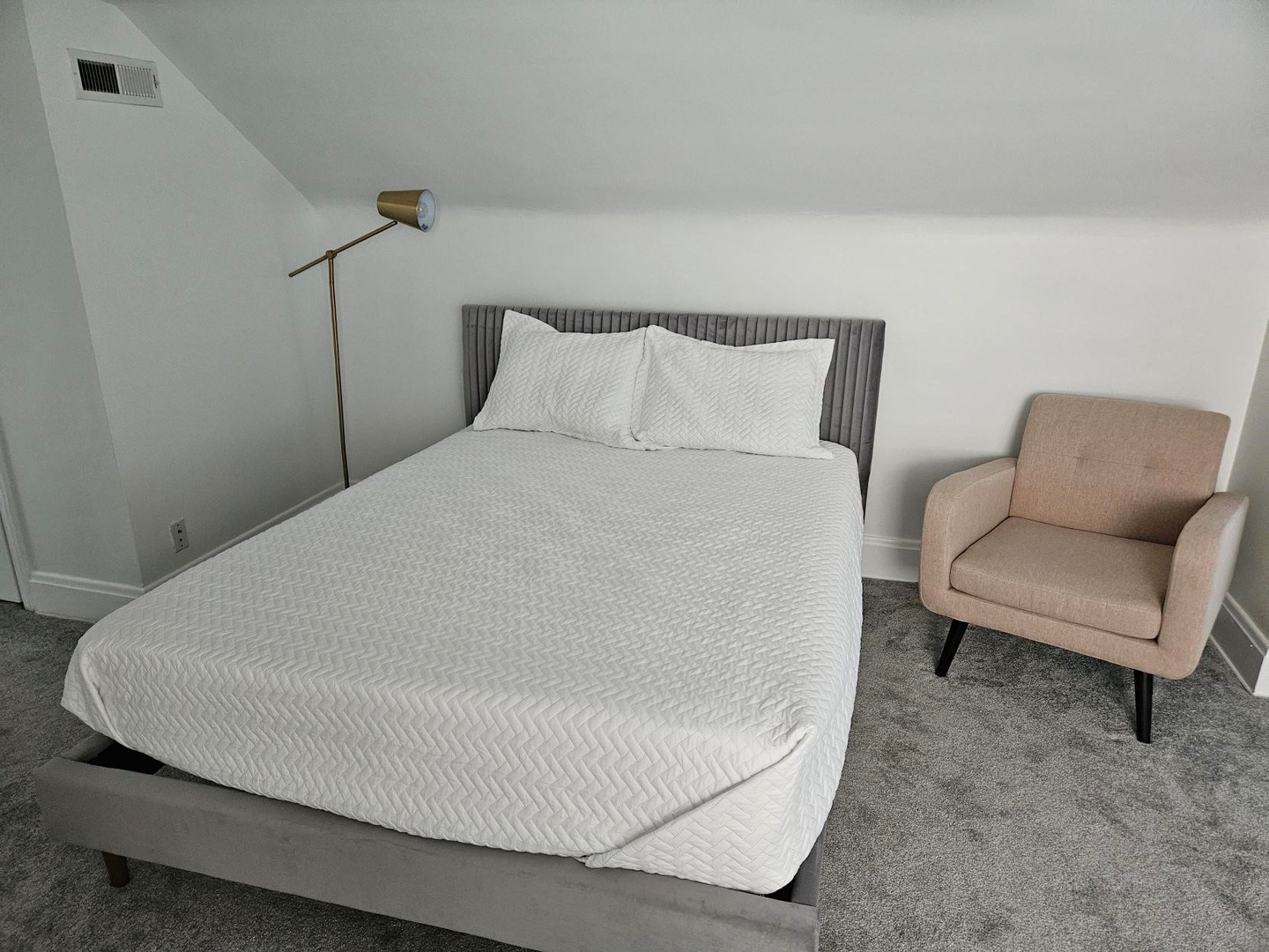 The 3rd floor attic bedroom area includes a cozy queen bed & armchair