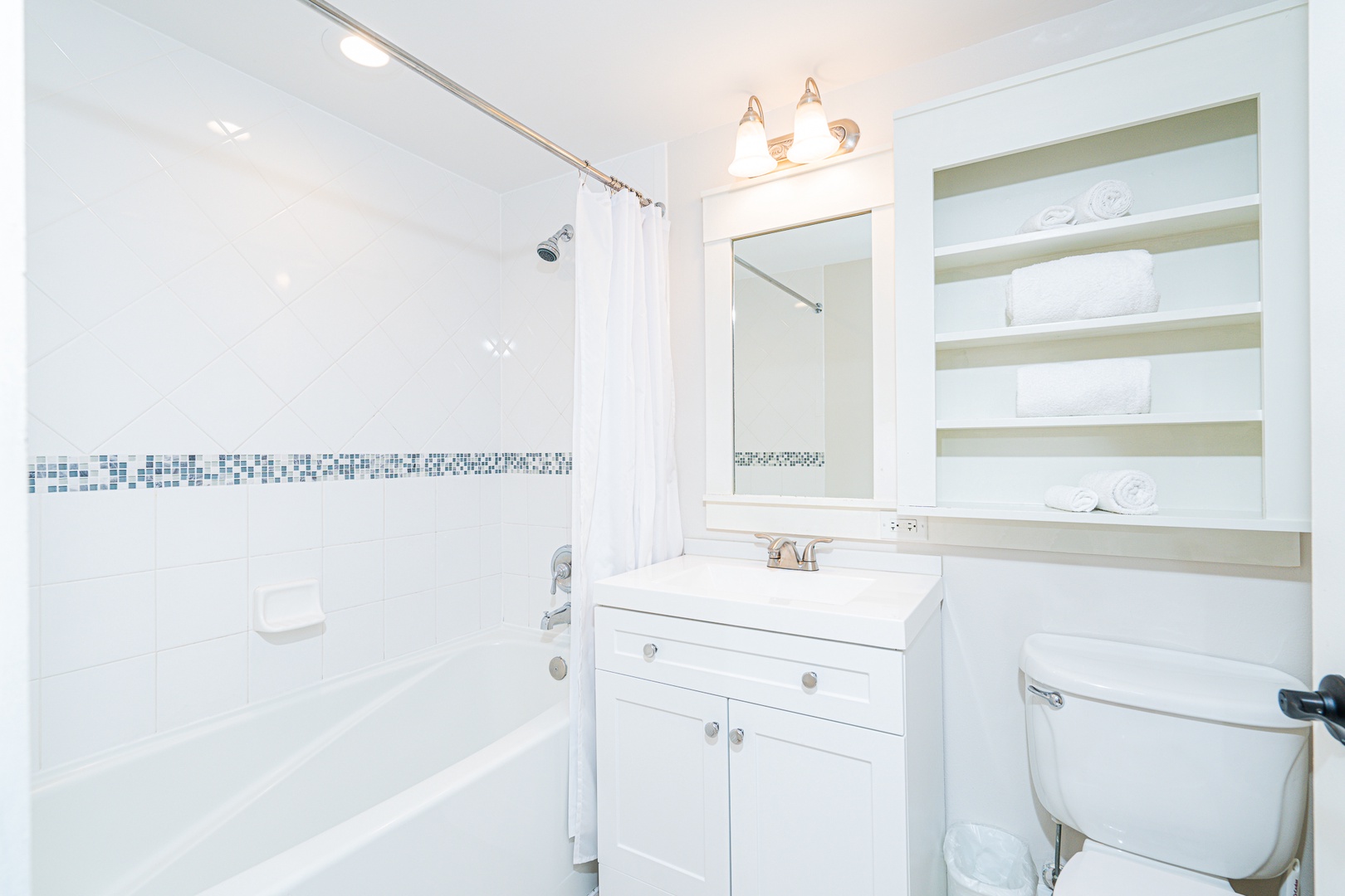 The airy full bathroom features a single vanity & shower/tub combo