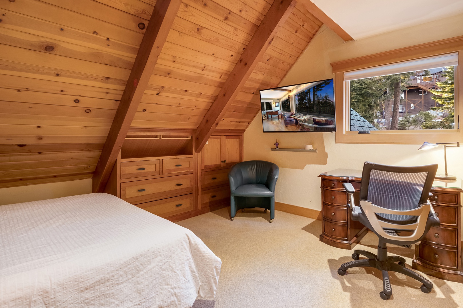 The cozy third-floor queen bedroom features a workspace with forest views