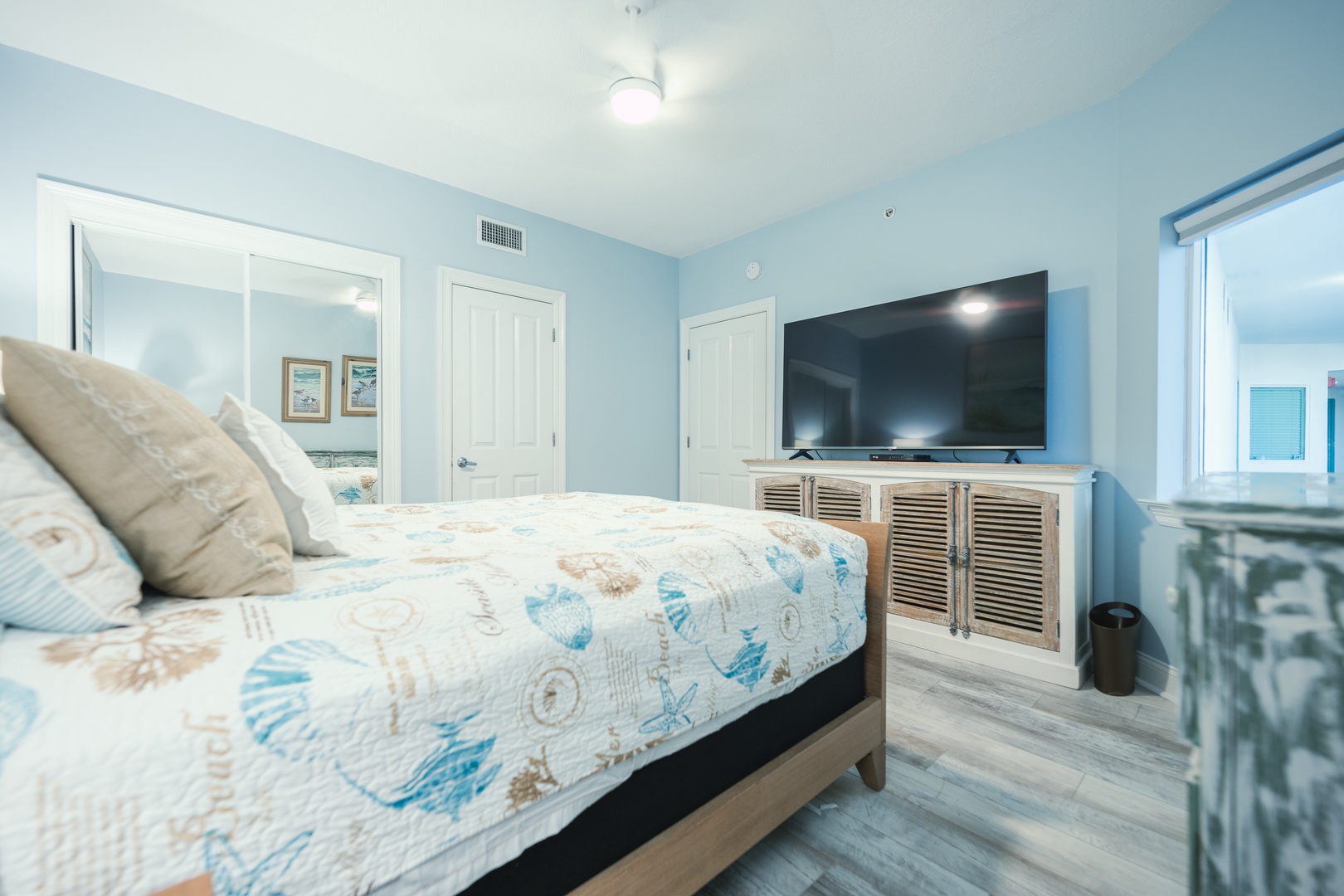 The serene second bedroom includes a queen-sized bed & Smart TV