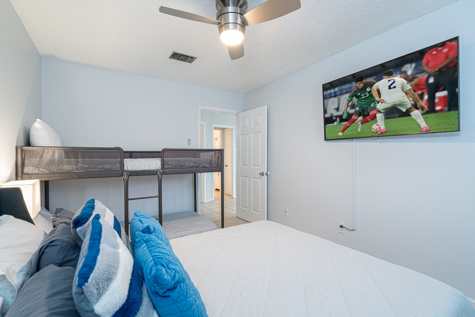 The 2nd bedroom showcases a queen-sized bed, twin bunkbed, & Smart TV