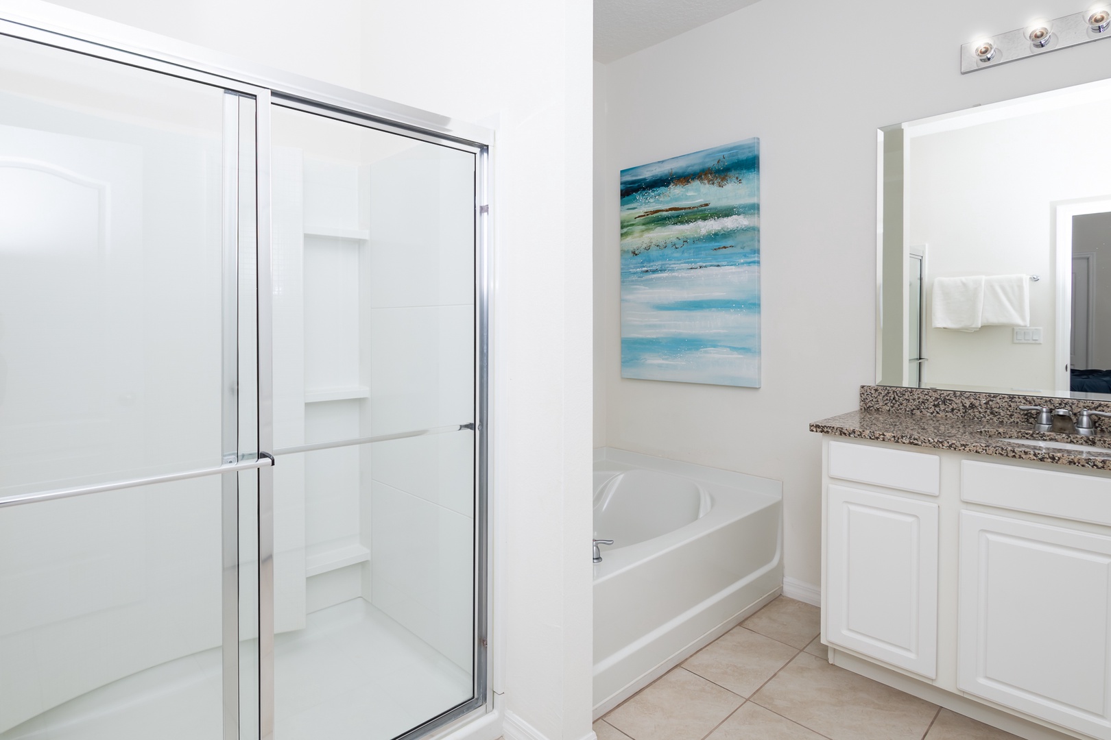 This ensuite bath features a double vanity, glass shower, and soaking tub