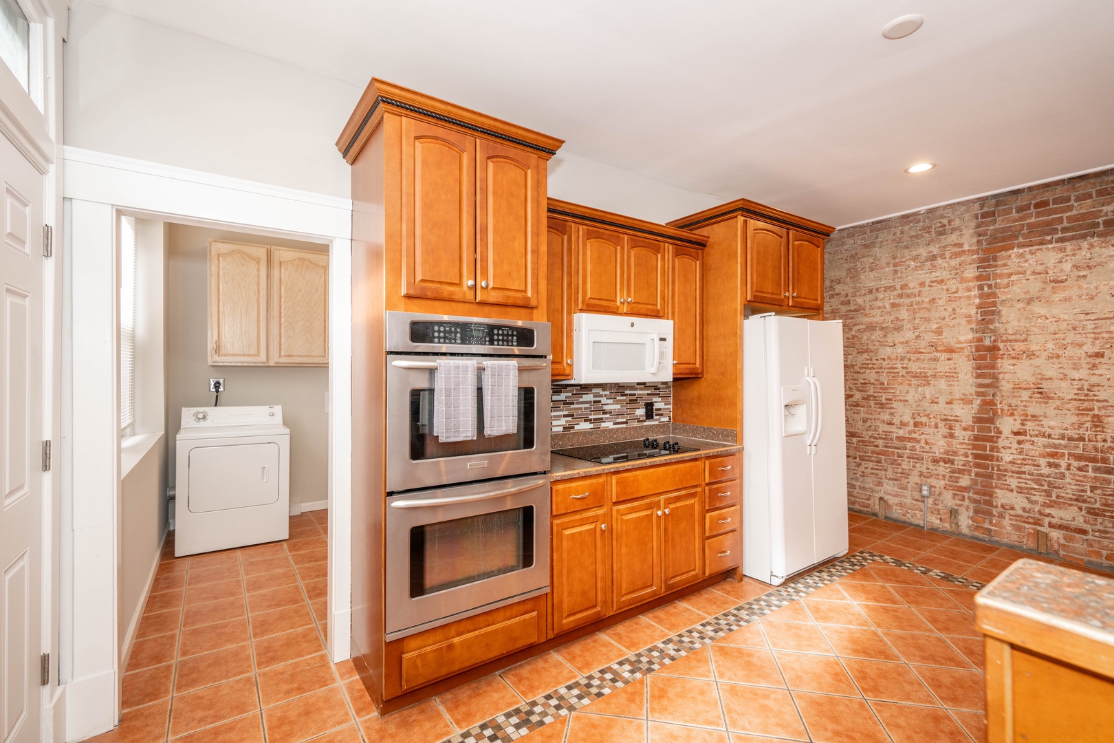 The kitchen showcases exposed brick, ample space, & numerous amenities