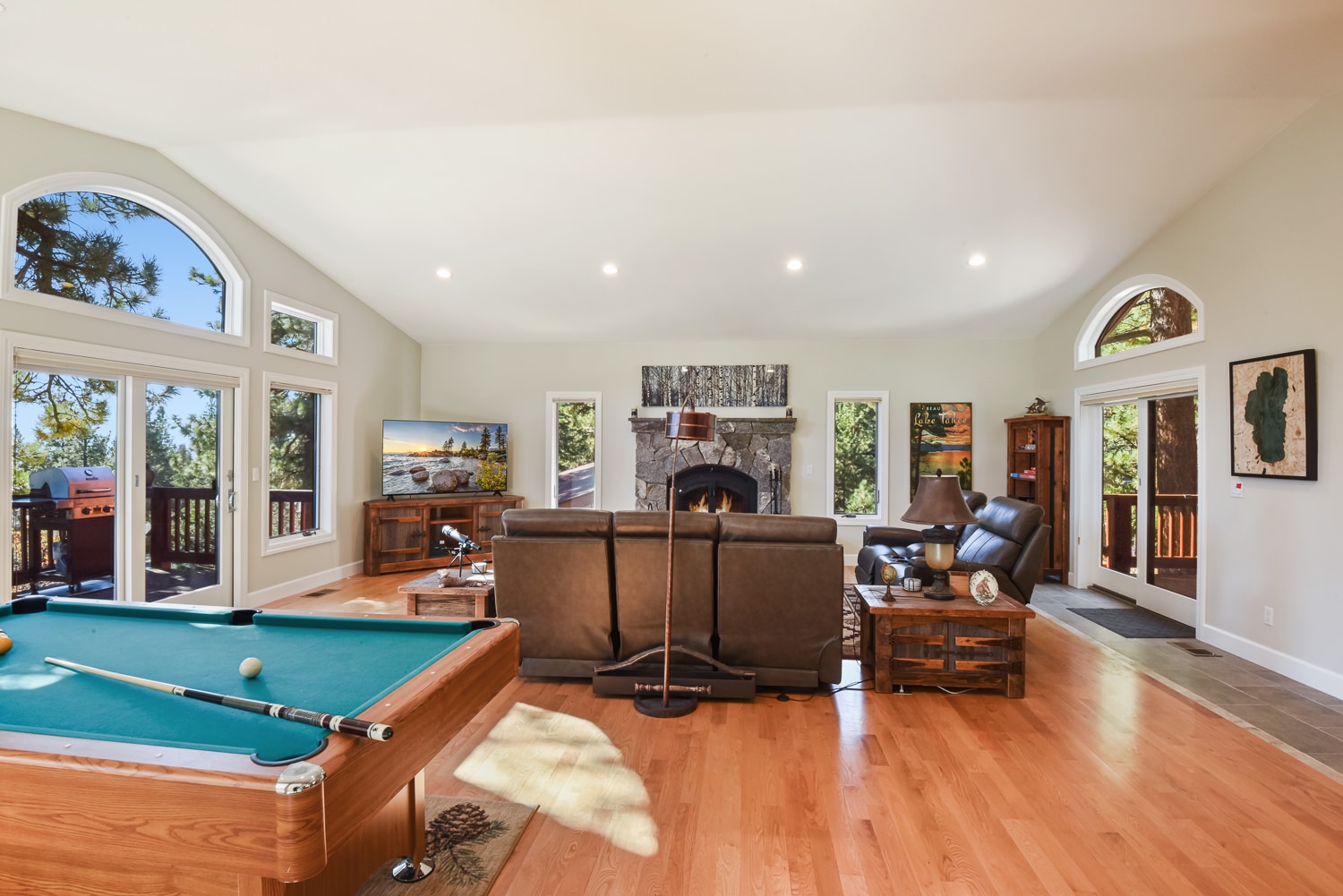Open living space with pool table, dart set, gas fireplace, Smart TV, and deck access
