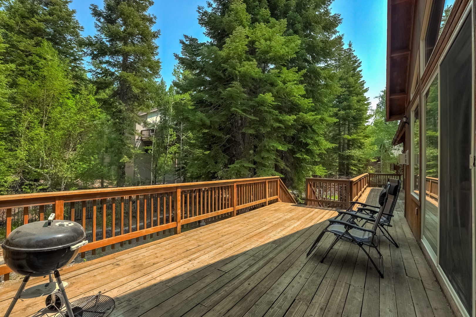 Spacious deck with gas BBQ, forest view, and access to backyard