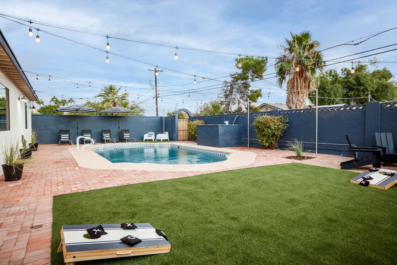 Private heated pool, resort-style lounge chairs, fire pit, outdoor dining, grill, and grassy area for corn hole