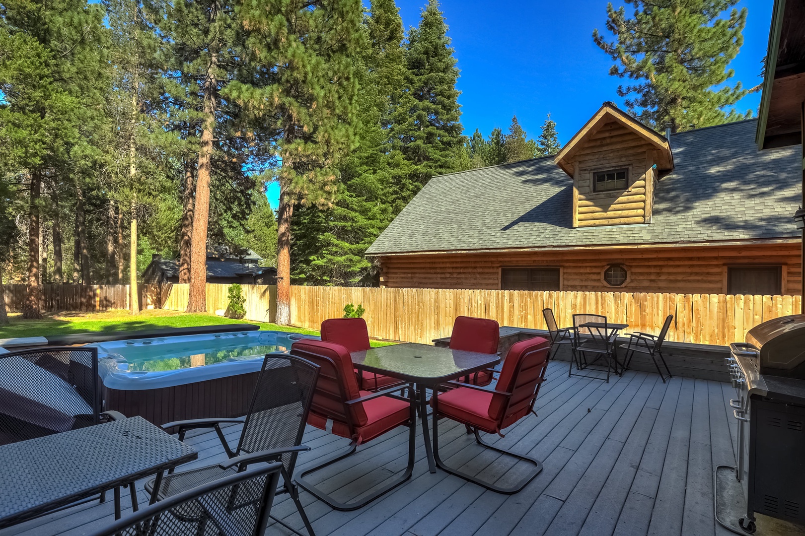 Spacious fenced in backyard with hot tub, gas BBQ, and patio seating