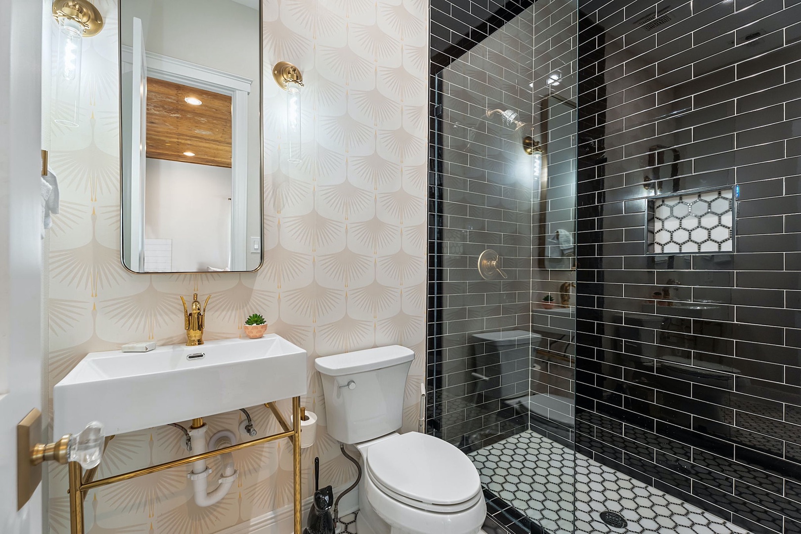 This full bathroom contains a pedestal sink & glass walk-in shower