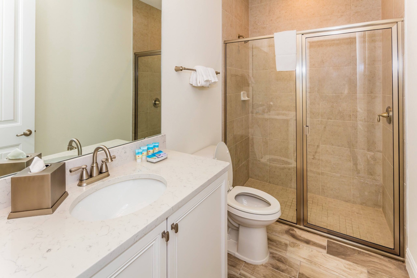 Shared bathroom with single vanity and glass-enclosed shower