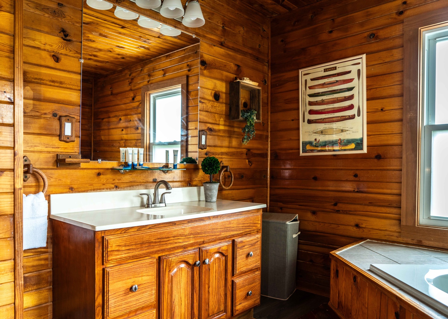 The full bath features a single vanity, glass shower, & luxe soaking tub