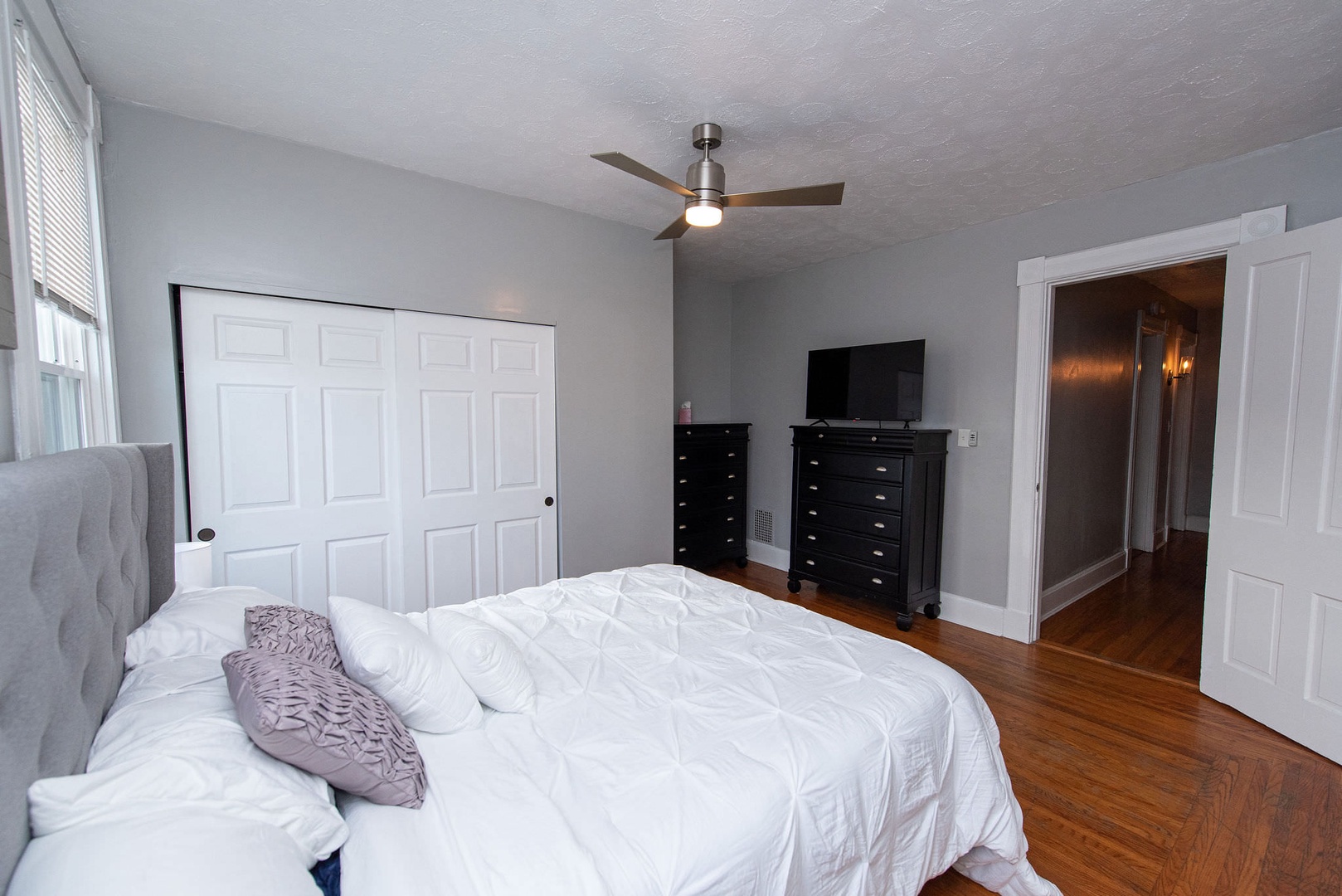 The primary bedroom includes a queen bed, Smart TV, & ceiling fan