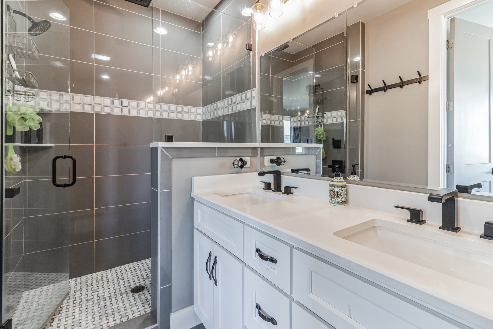This ensuite bathroom includes dual vanities & a spa-like glass shower