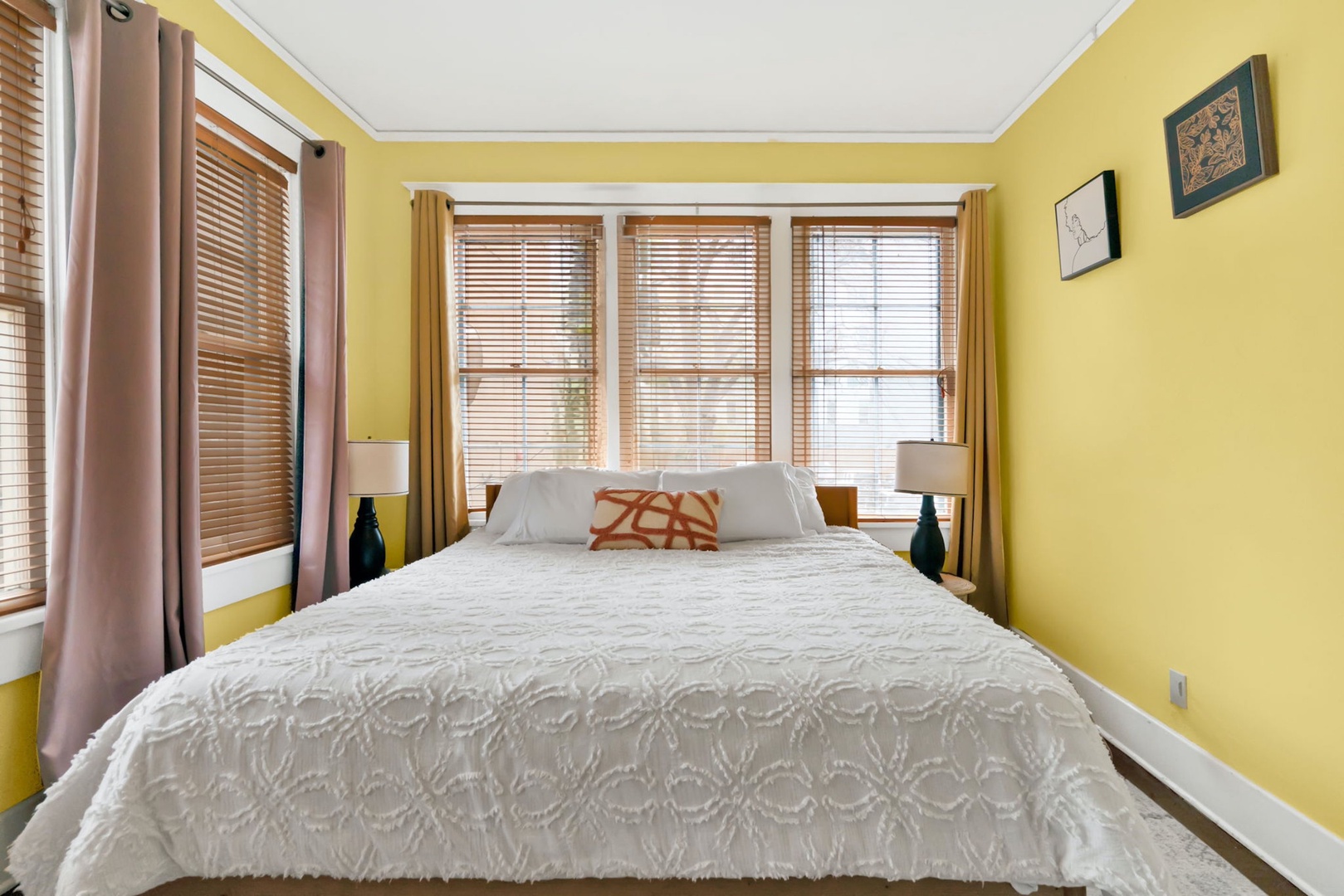 The second cheerful bedroom features lots of windows & a cozy king bed