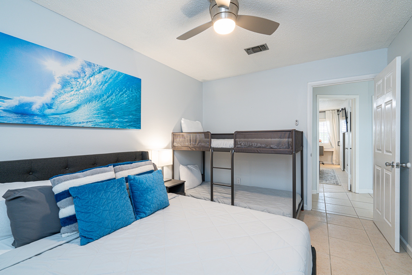 The 2nd bedroom showcases a queen-sized bed, twin bunkbed, & Smart TV