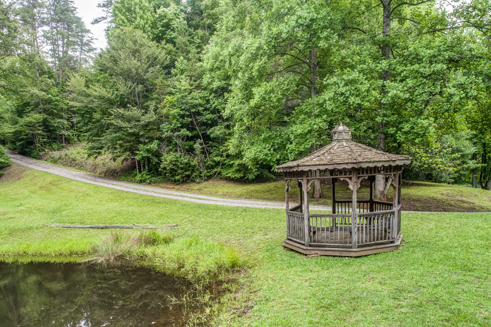 A lovely gazebo off the driveway overlooks the pond