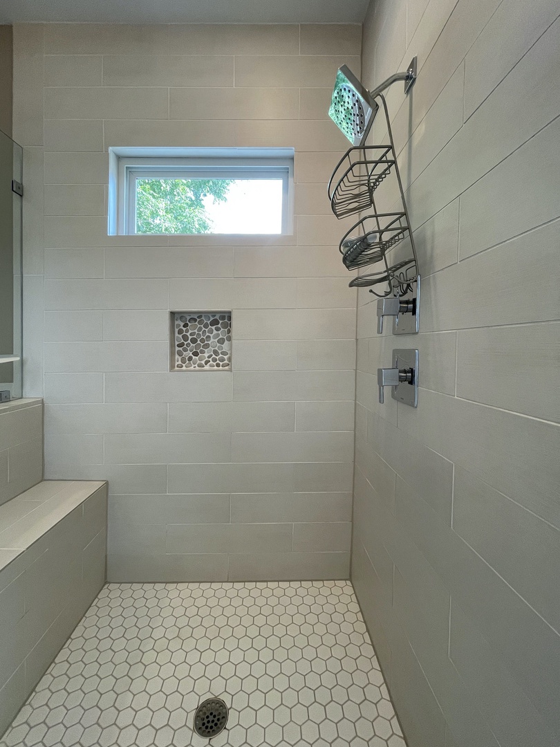 En suite bathroom with soaking tub, dual sinks, and standing shower