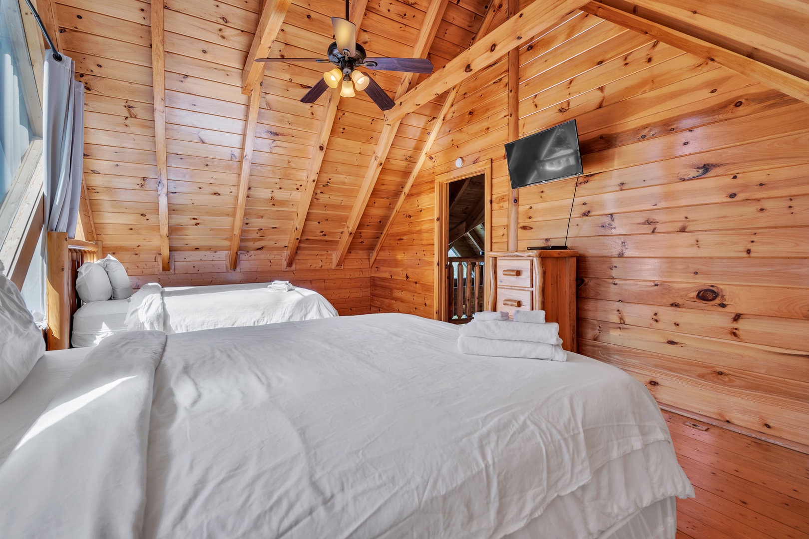 This light-filled 4th floor bedroom offers a pair of queen beds, ceiling fan, & TV