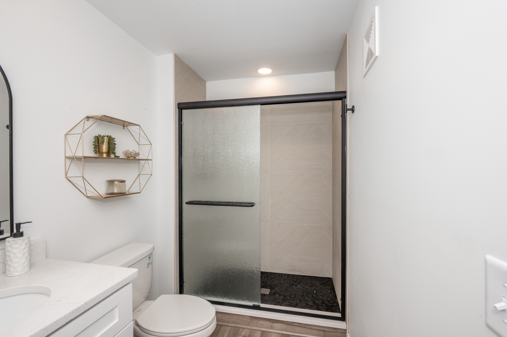 The chic bathroom offers a single vanity and spa-like glass shower
