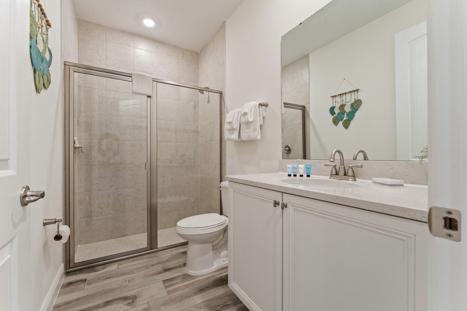 Shared bathroom with single vanity and glass-enclosed shower