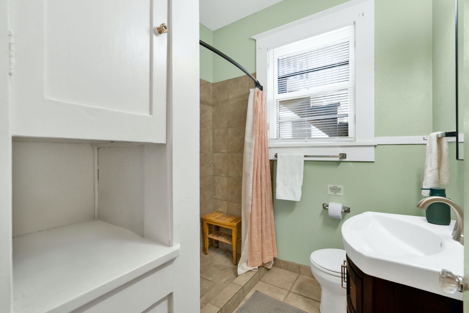 The full bathroom features a sleek single vanity & walk-in shower