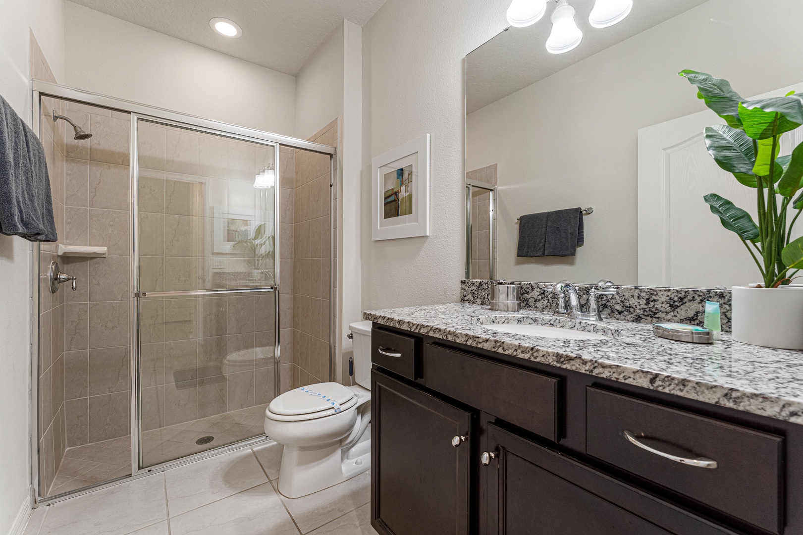 This shared bathroom contains a single vanity & shower/tub combo