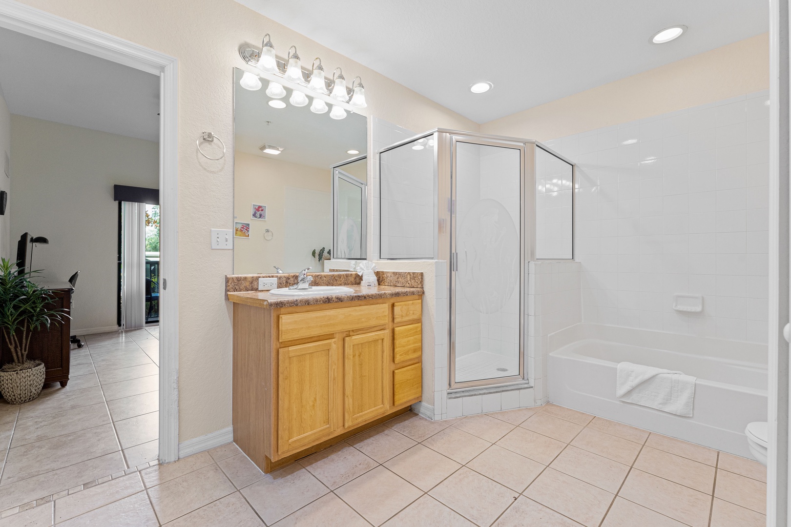 A single vanity, shower, & tub await in the shared ensuite bath