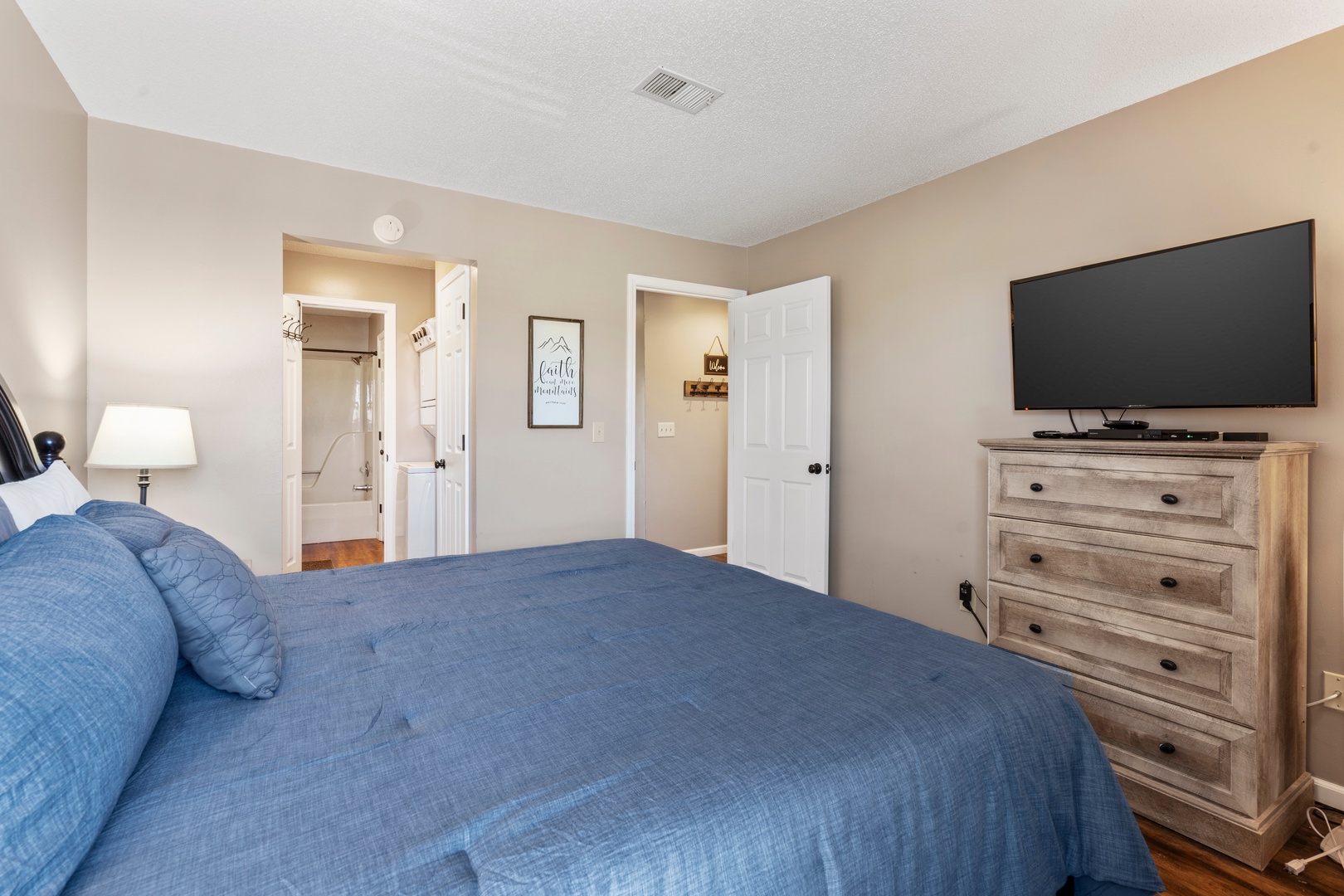 The tranquil primary suite boasts a plush king bed, ensuite, & TV