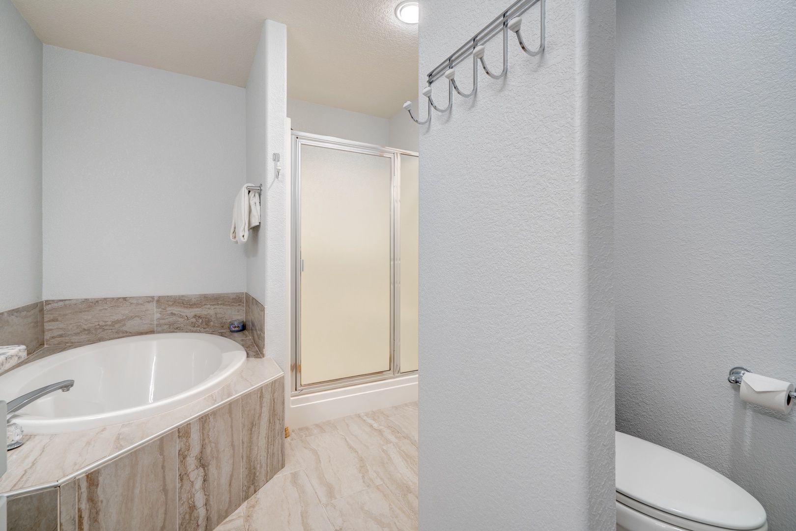 The final ensuite bath showcases a single vanity, shower, & luxe soaking tub