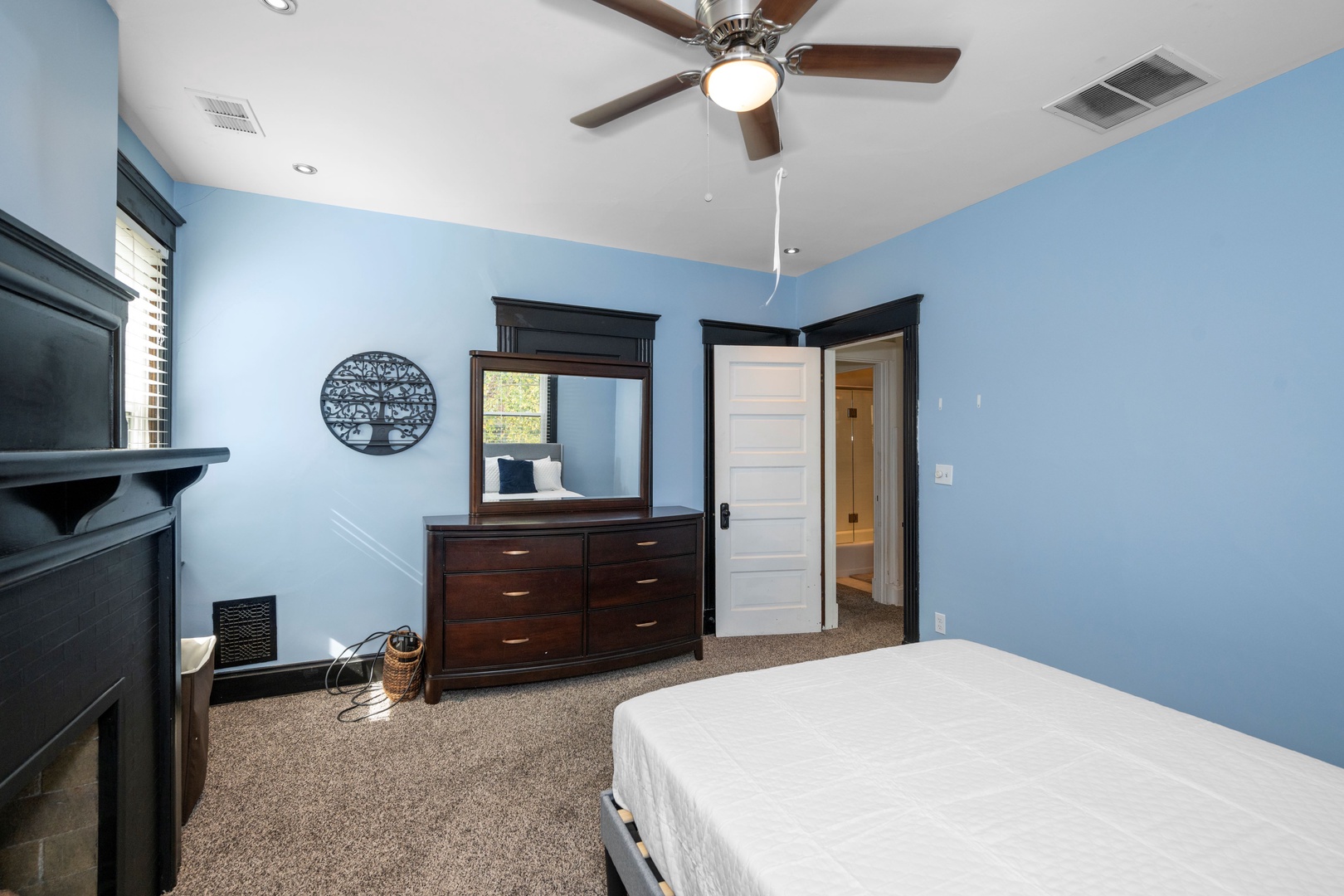 The 1st of 2 queen bedrooms on the second level, with a dresser & ceiling fan