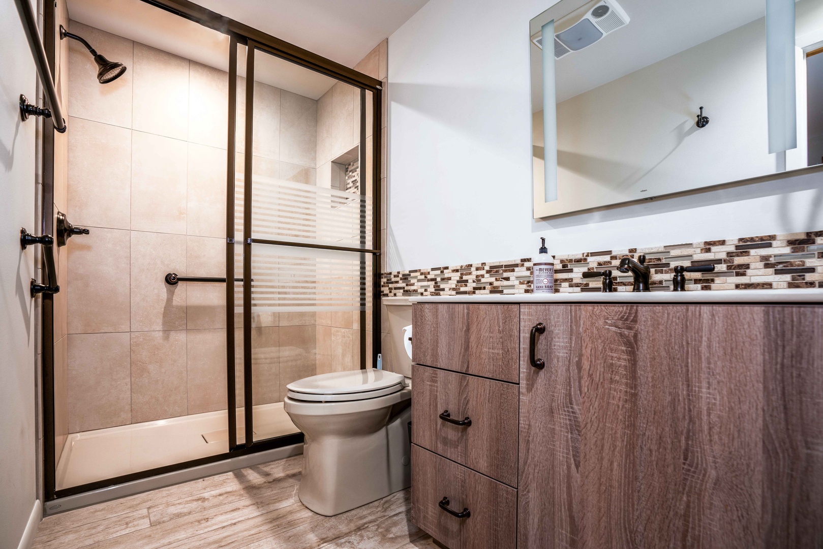 This full shared bathroom includes a single vanity & glass shower